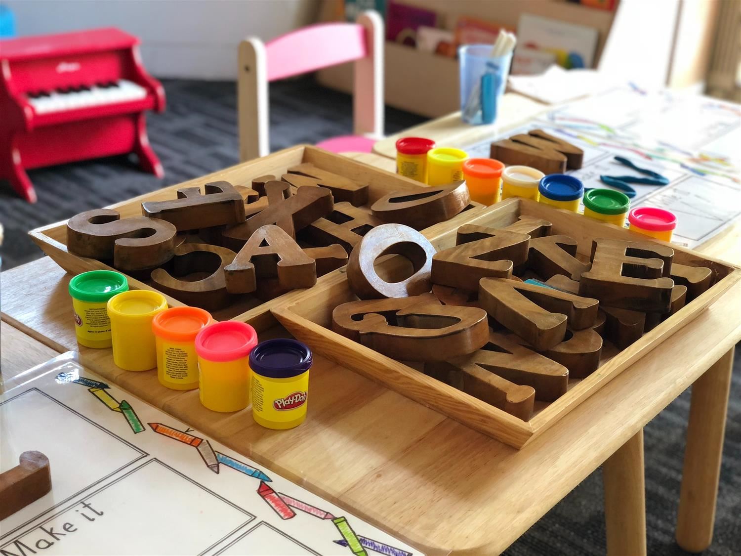 Photo of kindergarten desk with clay, letters, placemat and small chair